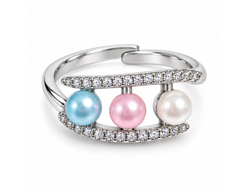 A silver-toned open band ring featuring three round pearls in light blue, pink, and white, accented by rows of small clear stones on curved bands, shown on a white background.