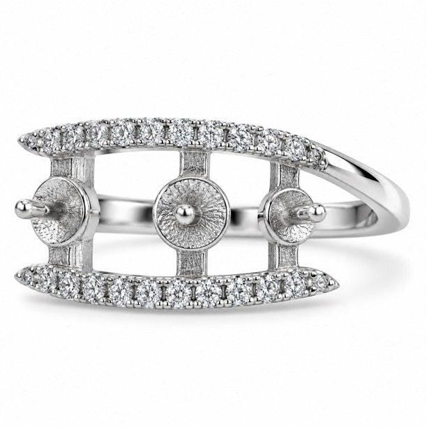 A silver-toned ring featuring a curved top and bottom band paved with small clear stones, with three circular pavé sections on the sides and a polished band, shown on a white background.